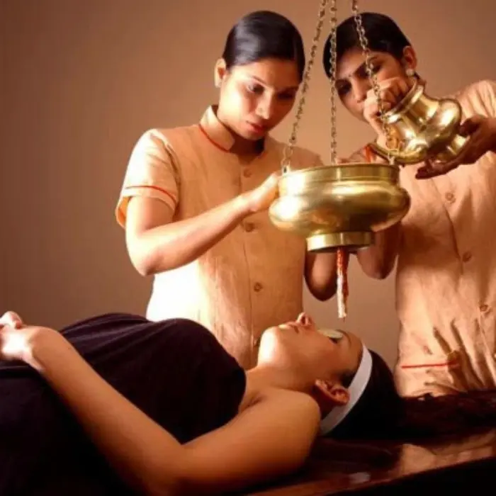 It is an image of two female professionals giving ayurvedic treatment to a female