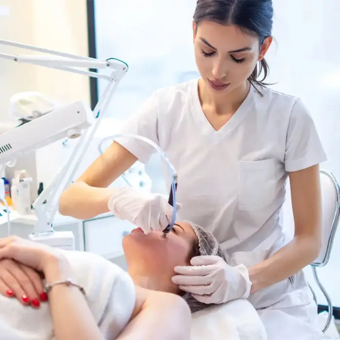 It is an image of skin clinic where a female doctor is giving skin treatment to female patient